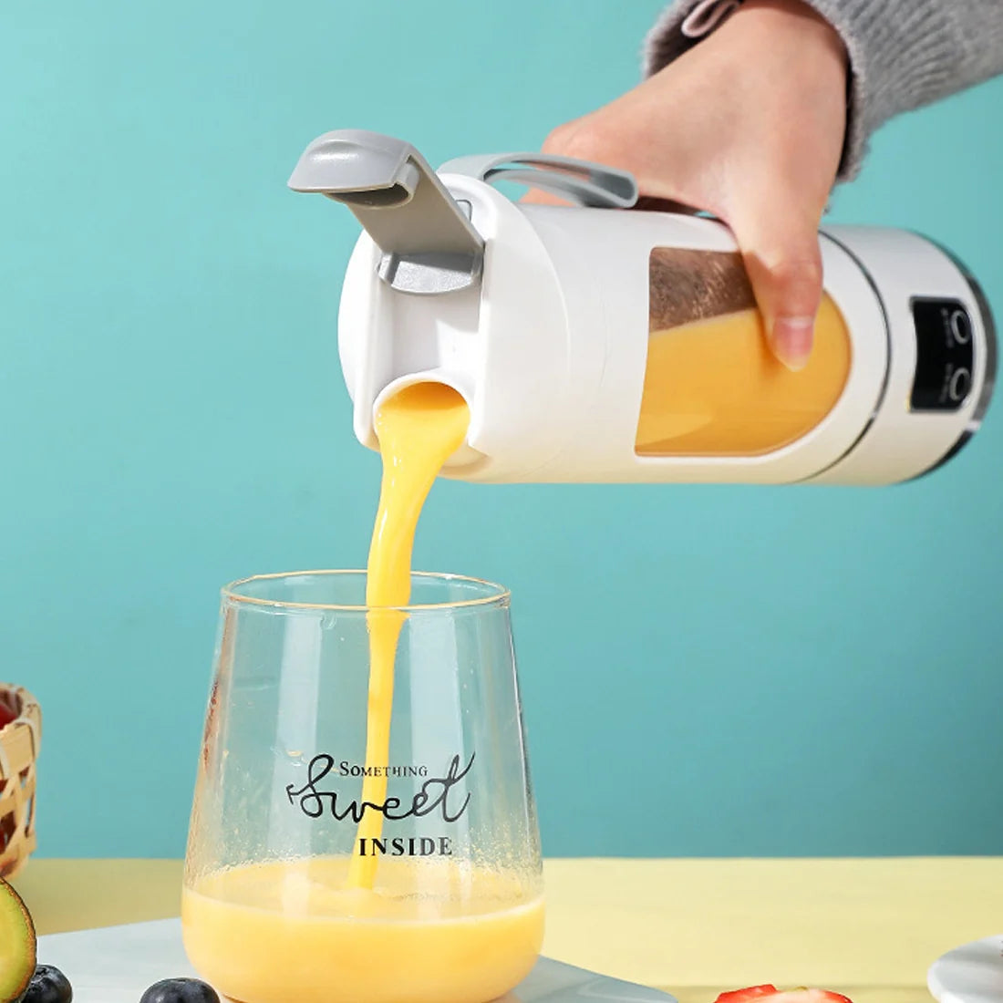 Pouring fresh juice from Portable USB Juicer Cup into a glass on a table.